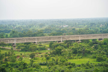 Aerial View of Lush Green Landscape with Concrete Bridge, Concrete Bridge Spanning Over Verdant Forested Valley, Panoramic Scenic Landscape with Bridge and Forest in Morning Haze Adobe Stock Photo.