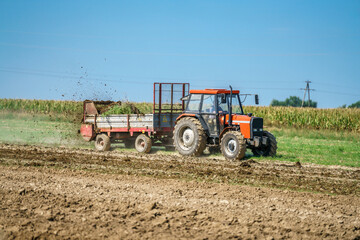 A tractor spreading manure on a field
