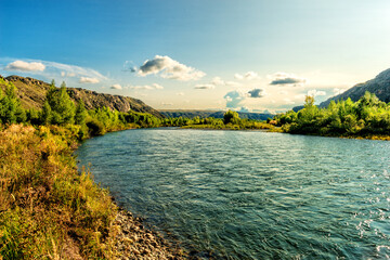 Naklejka premium Landscape of a river flowing through a plain among mountains