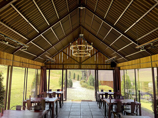 Typical rural countryside café or restaurant with rustic and vintage materials. Warehouse barnyard concept, with triangular asbestos roofing, and rope chandelier. Barnyard lawn concept theme.