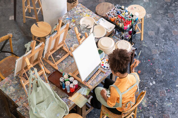 Young Girl Drawing in a Vibrant Painting Studio with Art Supplies and Canvases, Creative Artistic...