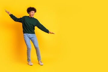 Full body portrait of nice young man balancing empty space wear sweater isolated on yellow color background