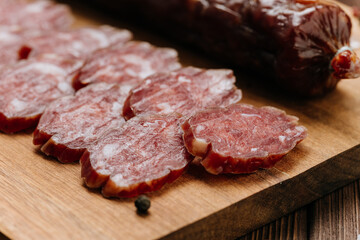 Close-up of thinly sliced salami on a wooden board, showcasing rich marbling and gourmet quality