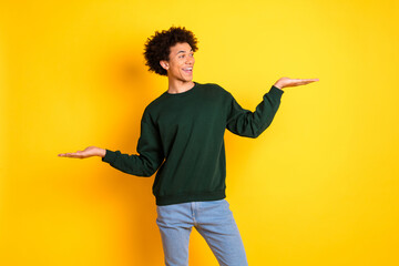 Portrait of nice young hold empty space man wear sweater isolated on yellow color background