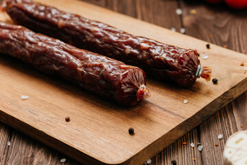 Smoked salami sticks on a wooden board with herbs, perfect for charcuterie boards and gourmet snacks