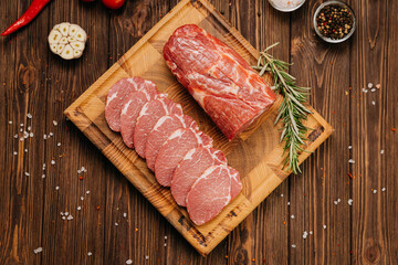 Fresh raw pork loin with rosemary on a wooden cutting board, perfect for cooking or grilling recipes
