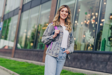 Portrait of pretty young girl carry rucksack wear denim jacket walk street outdoors