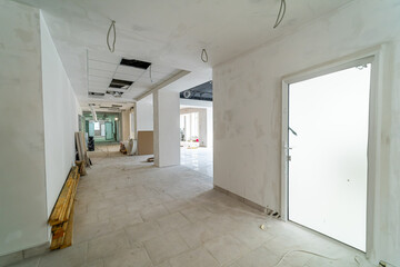 Interior renovation of a building with ongoing construction work. The hallway of a building shows ongoing renovations with exposed walls and unfinished areas