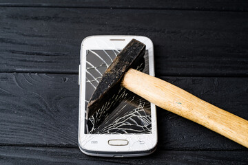 Person smashing a smartphone with a hammer on a black wooden table. A person is breaking a...