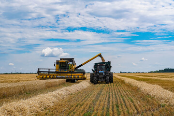 Harvesting machinery working in golden fields under a blue sky. Large harvesting equipment operates...