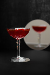 Vampire's Kiss Cocktail. Dracula's Blood Cocktail or Mocktail on dark background with reflection in mirror. Drink for Halloween with plastic vampire teeth as a garnish. Festive food and beverages.