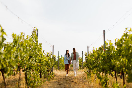 Couple strolls hand in hand along a sunlit path amidst lush vineyards during a warm afternoon - Powered by Adobe