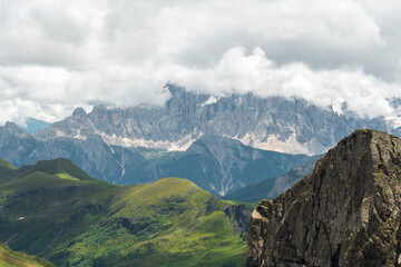 Monte Civetta (Belluno) rocky mountain background, green grass and rocky peak foreground on a cloudy day. Dolomites