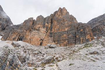 Vertical rocky mountain peak of Sella Group on a cloudy day. Climber going to via ferrata Cesare Piazzetta at the Piz Boè (Pordoi Pass), Dolomites