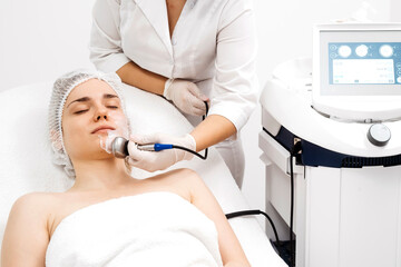 A cosmetologist performs RF lifting and ultrasound facial tightening in a modern salon. This...
