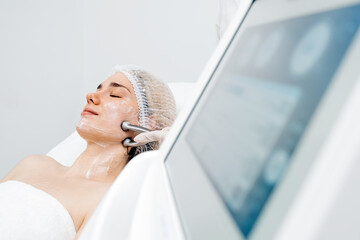 A cosmetologist performs RF lifting for facial rejuvenation and tightening. This non-invasive...