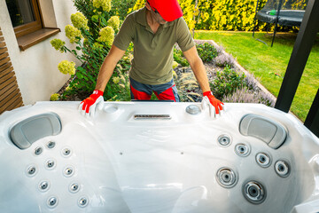 Technician Preparing a Hot Tub for Installation in a Residential Garden During Daylight Hours