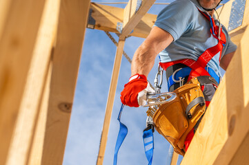 Construction Worker Preparing Safety Harness at a Building Site on a Sunny Day