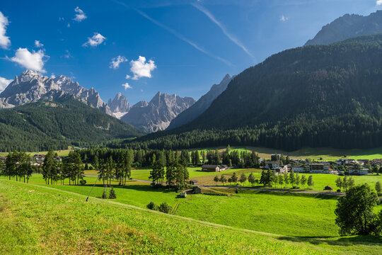 Vast Green Valley With Mountains and Sesto Village Under a Bright Blue Sky in the Dolomites
