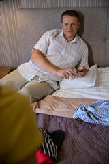 Fototapeta premium Man sits on the bed with a mobile phone
