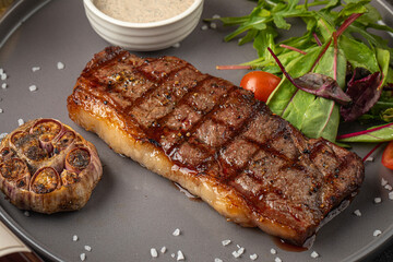 Closeup on portion of grilled beef steak with garlic and sauce