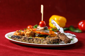 Assorted Mixed Grill Platter with Grilled Vegetables tikka boti seekh kabab of chicken, beef, lamb, mutton kebab and chops served in plate isolated on red background side view of arabic food