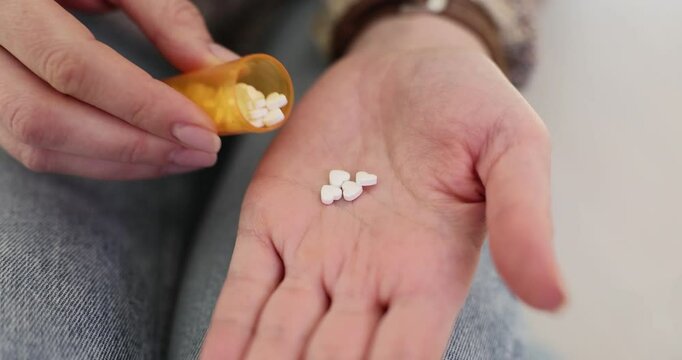 Young woman pours handful of pills on palm for taking. Lady preparing to take prescribed dosage to alleviate symptoms