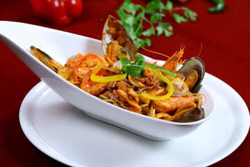Seafood Spaghetti pasta include calms, shrimp, prawn and noodles served in dish isolated on red background closeup side view of italian food