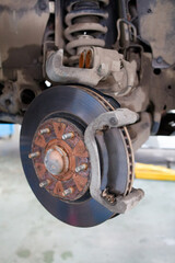 Closeup a disassembled car brake system during maintenance. Front disc brake of a car with a removed wheel. Shallow focus.