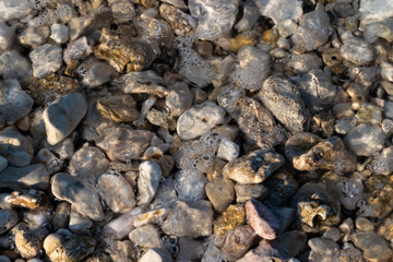 Sea water covers beach stones, bubbles in water