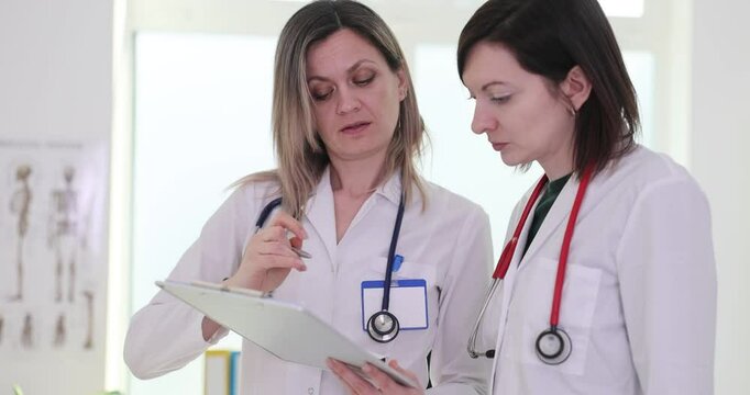 Female doctors review patient test results for future treatment. Workers considers various factors to reach consensus on appropriate course of action