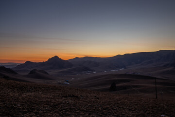 Obraz premium Orange dark sunset in rural Mongolia mountains, campsite sunset.