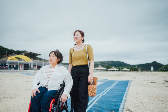 車椅子に乗った日本人女性が友人の女性と夏の沖縄を旅を楽しんでいる