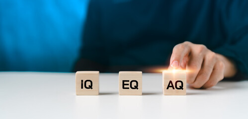 The letters IQ, EQ, and AQ on wooden blocks stand for intelligence quotient, emotional quotient,...