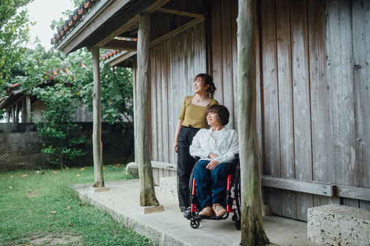 車椅子に乗った日本人女性が友人の女性と夏の沖縄を旅を楽しんでいる