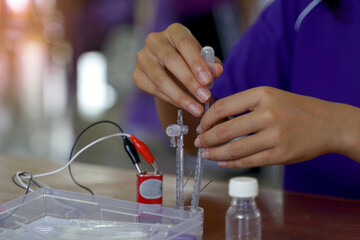 Asian school children conduct science experiments with kits Electrolysis, which is a method of...