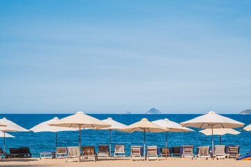 beach umbrellas with sun beds without people on a sandy beach against the background of the sea or ocean