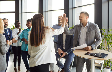 Happy professional team coaches, man and woman giving each other high five after successful...