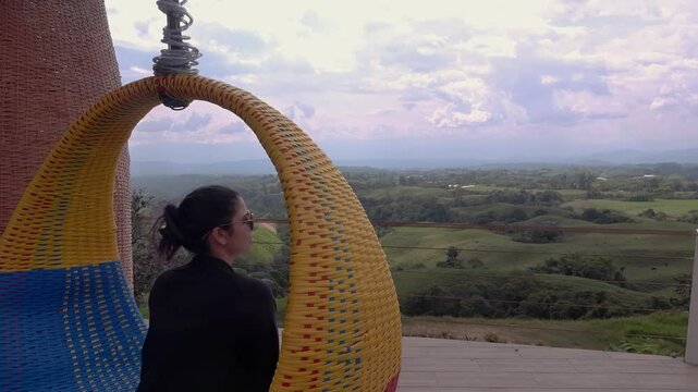 mujer contempla el eje cafetero desde una silla