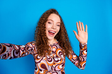 Photo portrait of attractive young woman take selfie photo wave hand hi dressed stylish colorful clothes isolated on blue color background © deagreez