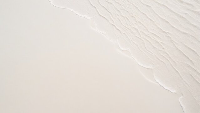 top view of waves on the edge of a white sand beach with texture as a background.