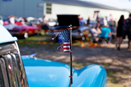 torn American flag on hood at car show
