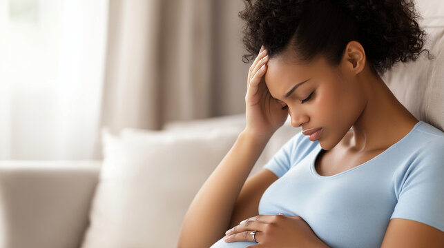 A pregnant woman in light blue attire, sitting on a sofa, holding her head with a pained expression while checking her temperature, her short black hair adding to the visual contra