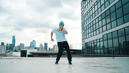 Stylish caucasian dancing man performing break dance at skyscraper. Portrait image of young happy...