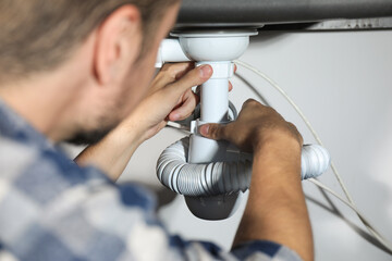 Professional plumber fixing piping system at home, closeup
