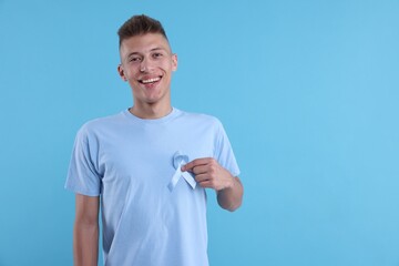 Prostate cancer awareness. Man with light blue ribbon as symbol of support on color background....