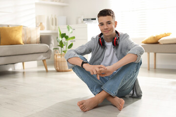 Full length portrait of teenage boy sitting on floor at home. Space for text