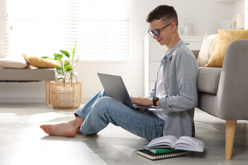 Full length portrait of teenage boy studying with laptop at home. Space for text