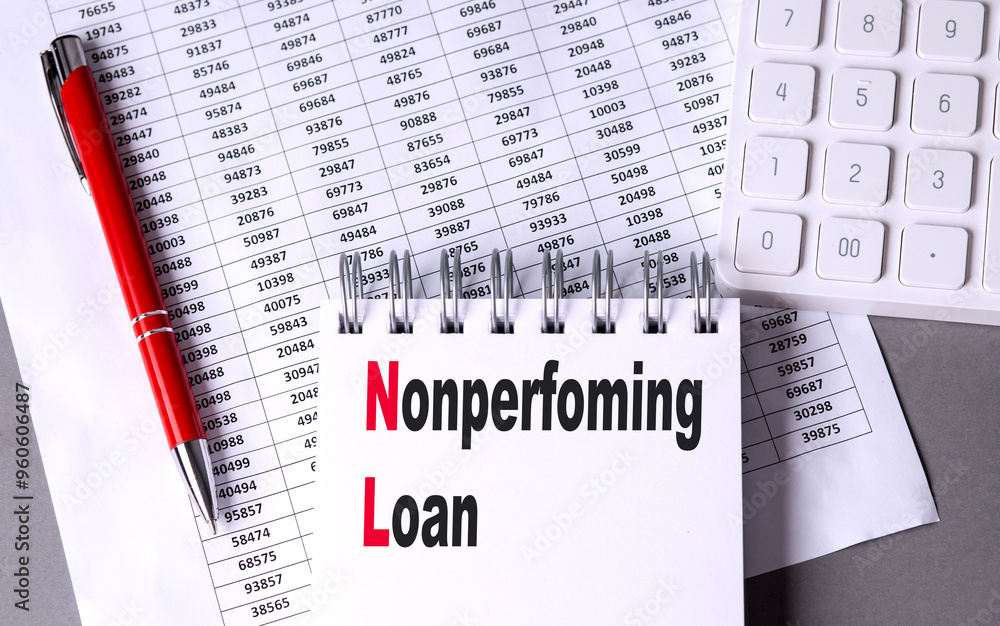 Poster notebook with the text nonperforming loan on a desk, surrounded by financial data sheets, a red pen,