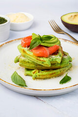 Belgian waffles with spinach, red fish and avocado on a light background.